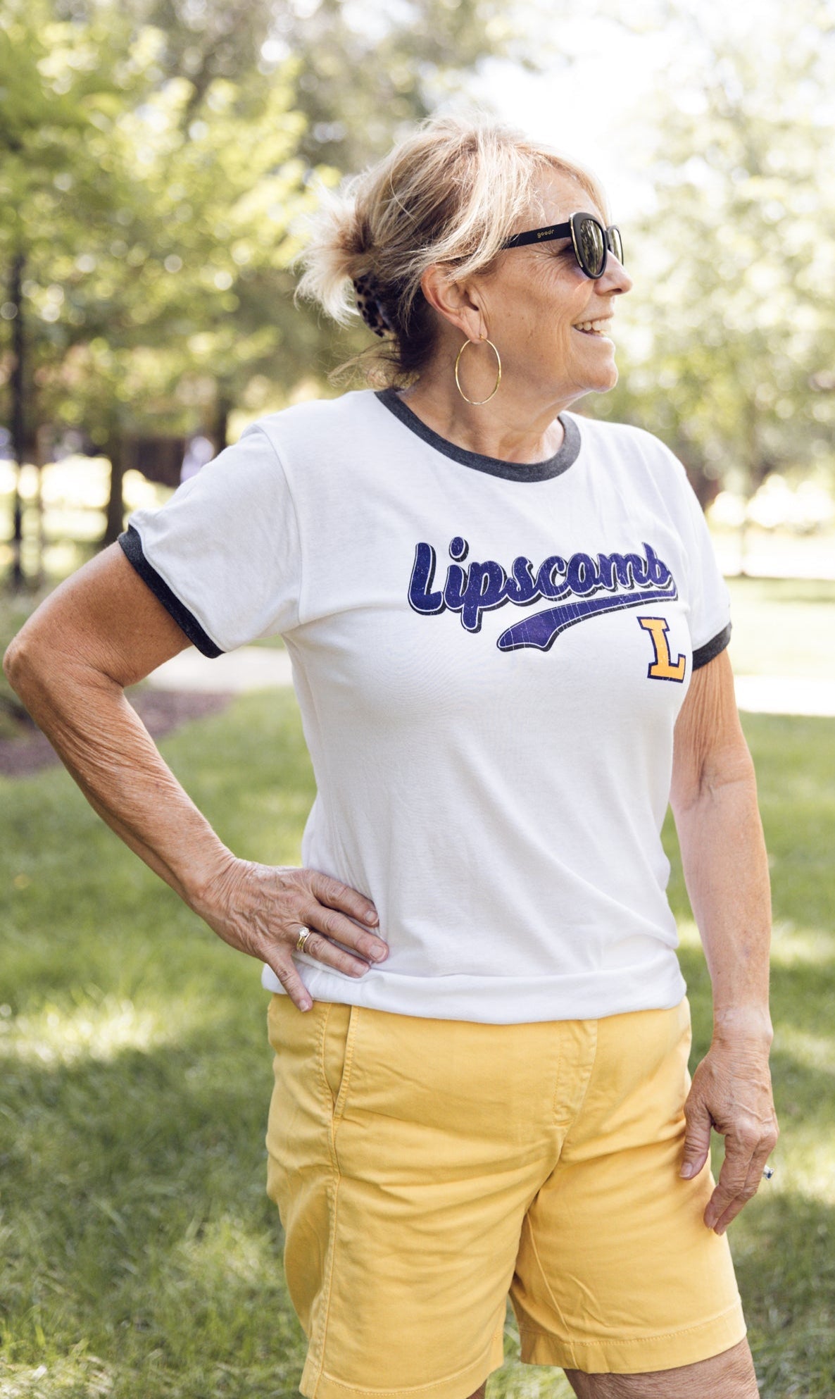 Woman wearing a white t-shirt with 'Lipscomb' printed on it, standing outdoors.