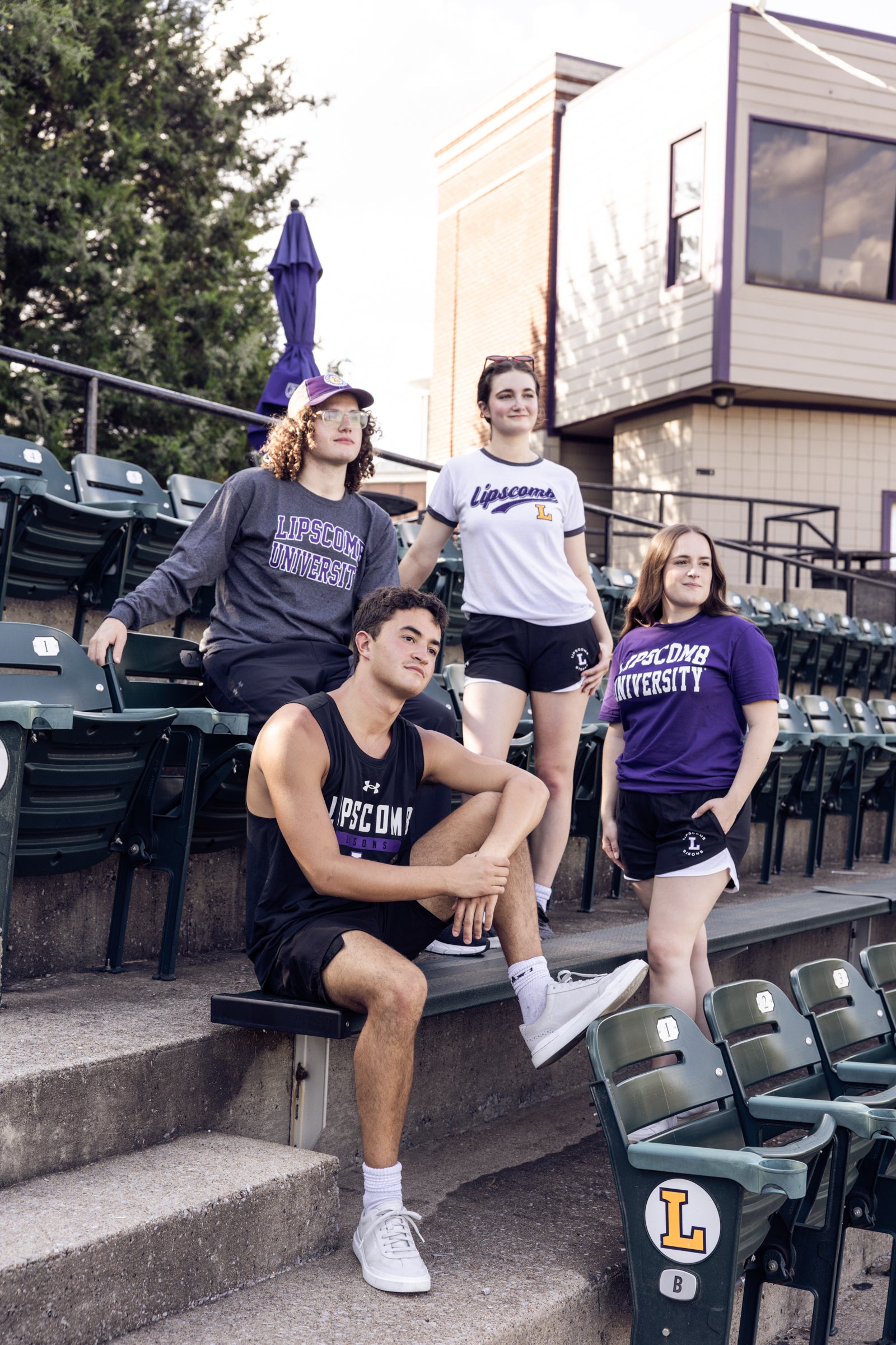 A group of students wearing Lipscomb gear standing and sitting in the stands 