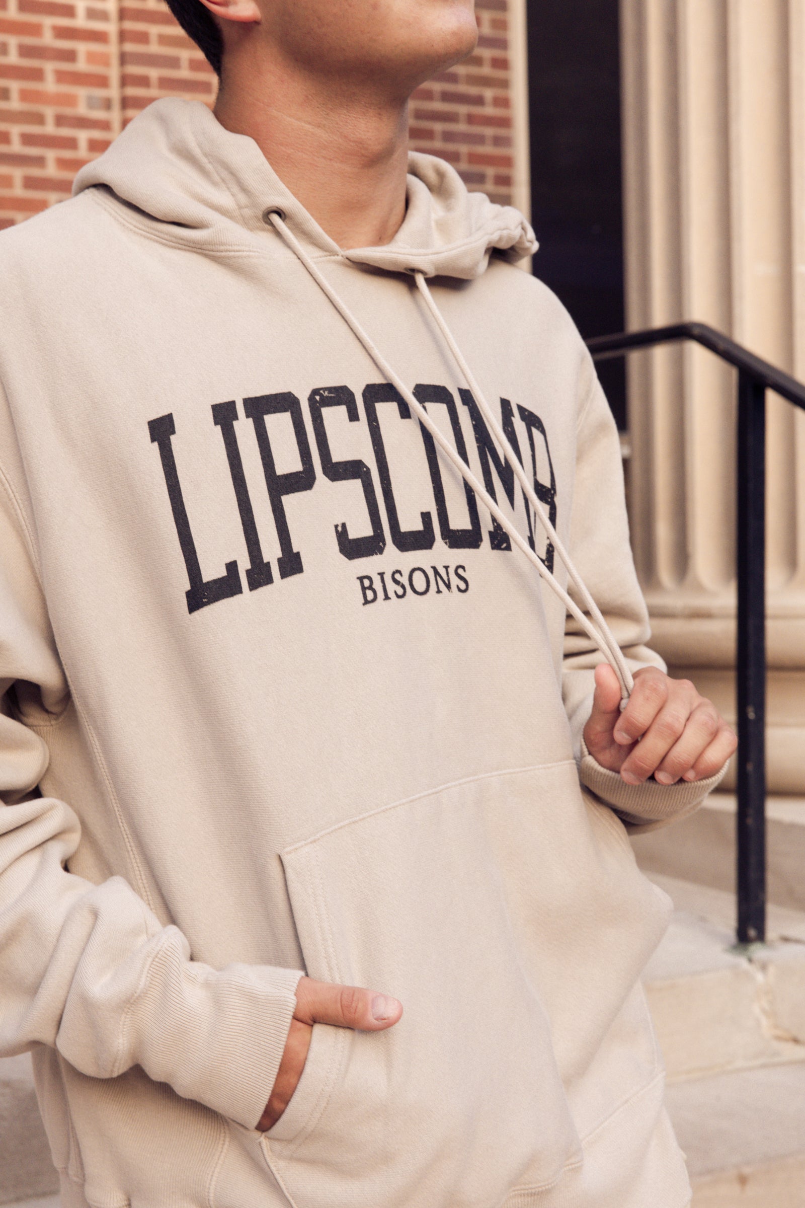 Person wearing a beige hoodie with 'Lipscomb Bisons' text, standing outdoors.