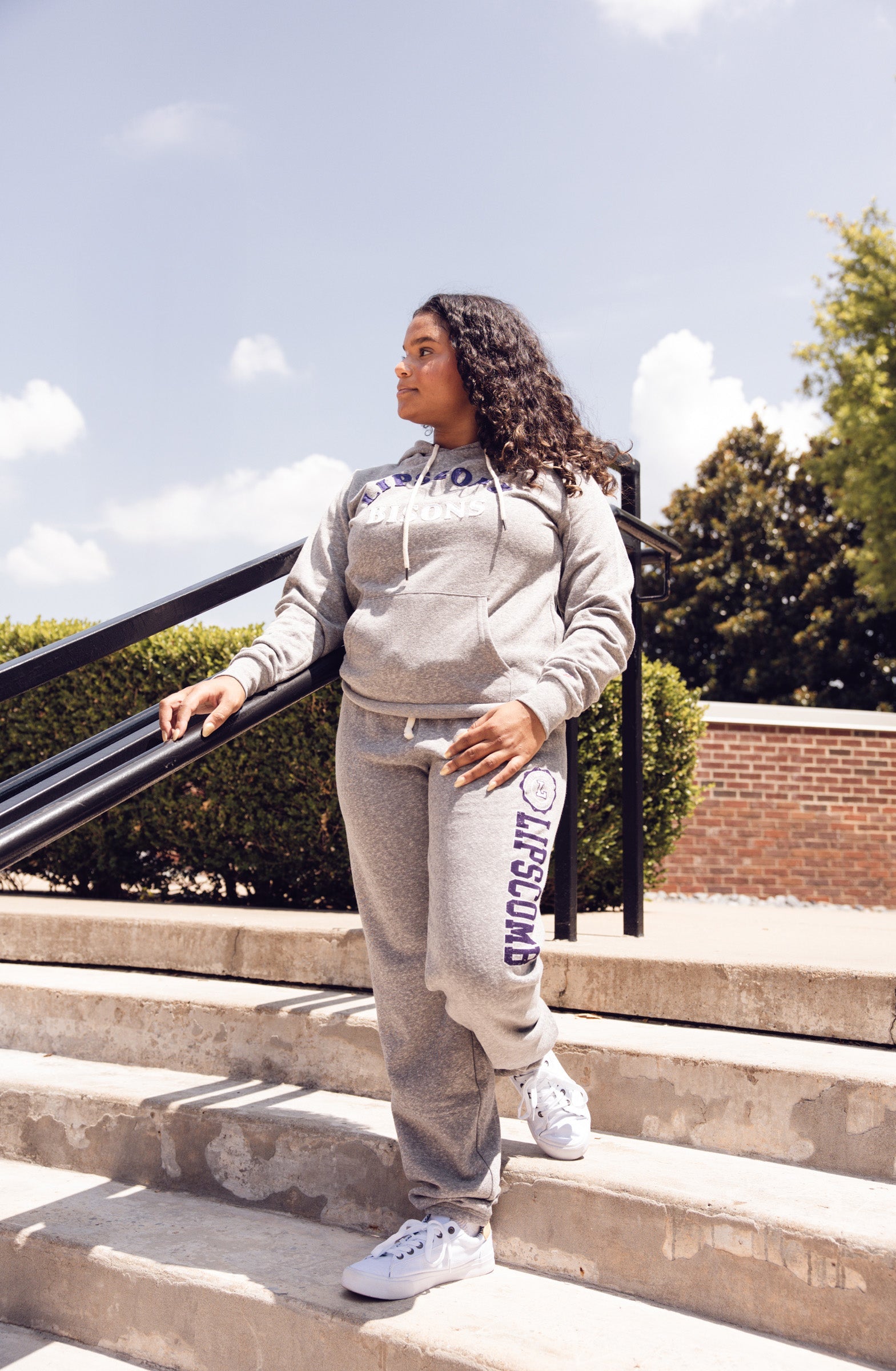 Person wearing a gray tracksuit with Lipscomb branding on outdoor steps.